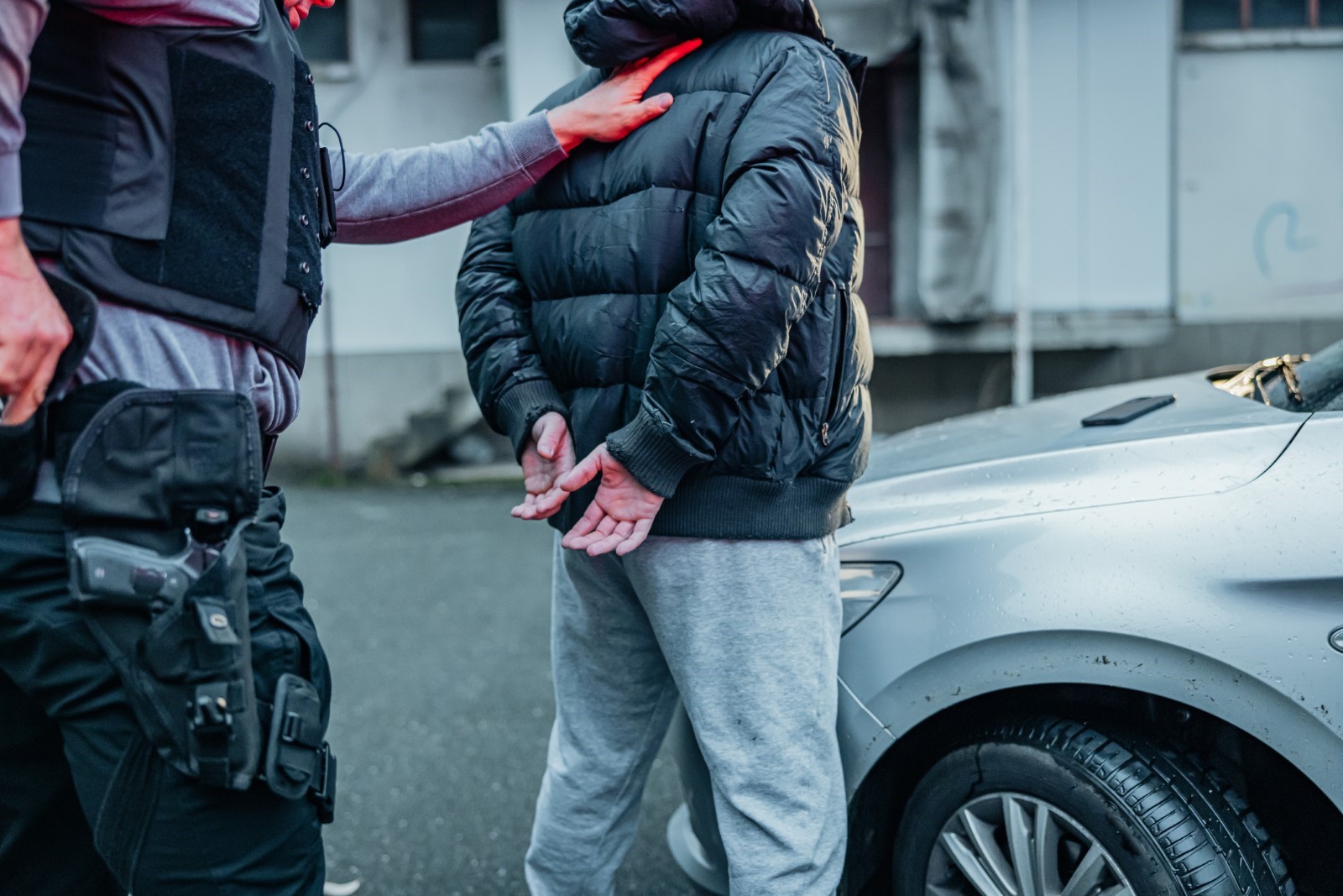 A person in a vest standing next to a car

Description automatically generated